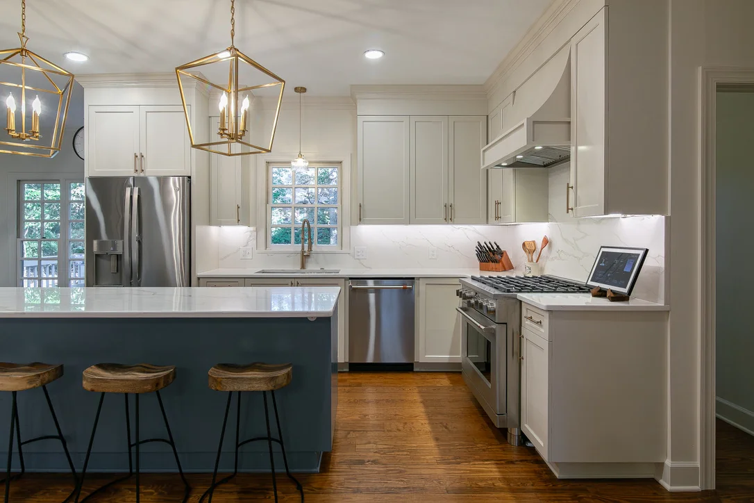 VanFleet Homes kitchen remodel with white cabinets, a blue island, and brass pendant lights