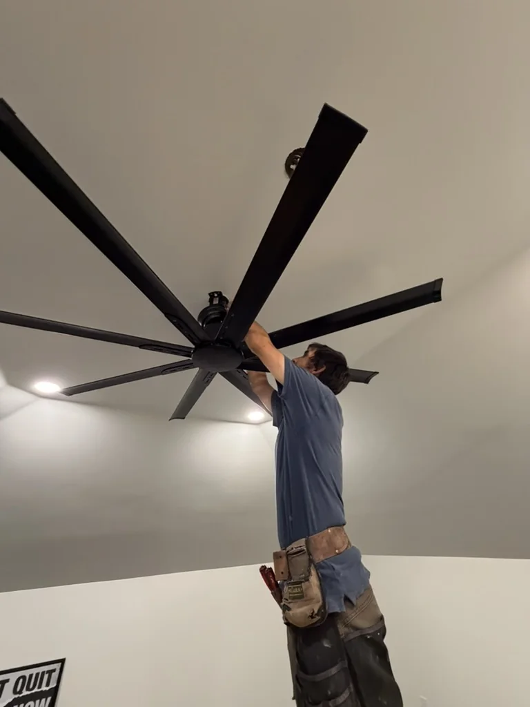 Installer fitting the large black fan in the attic gym