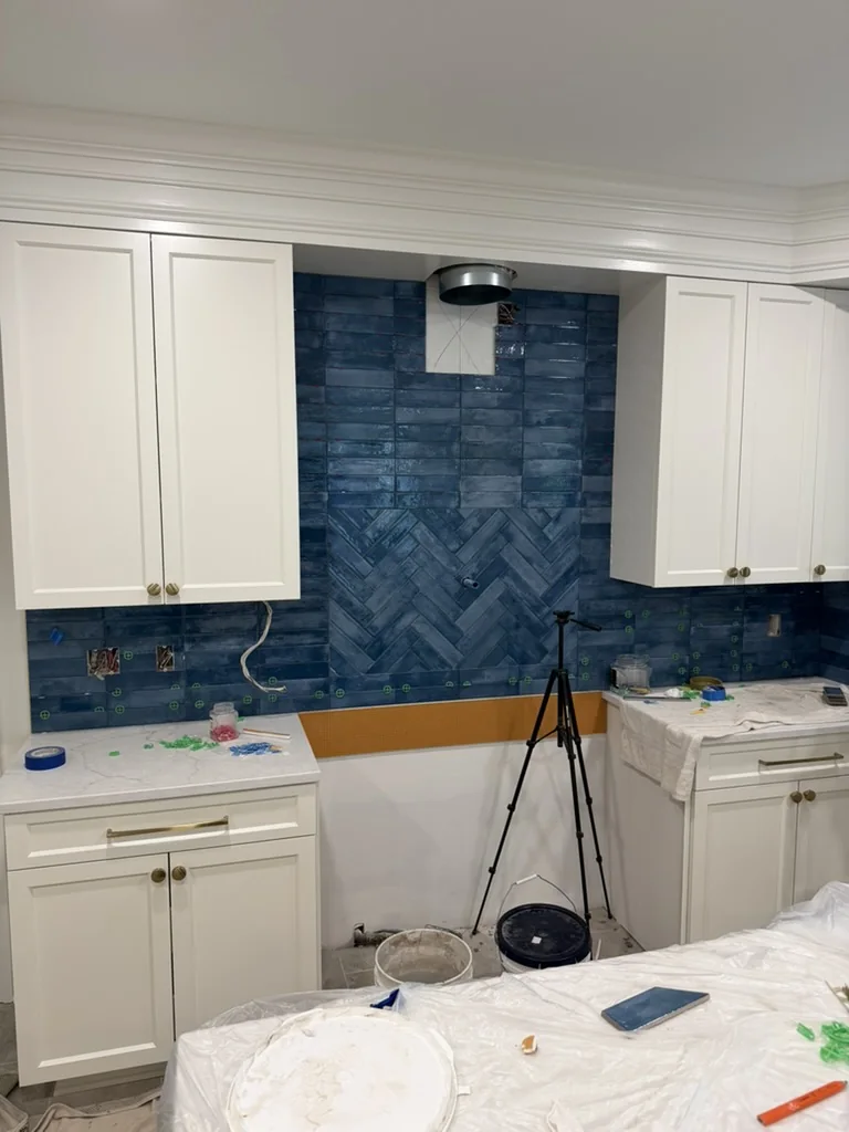 Blue kitchen backsplash tile installation with a herringbone feature behind the range