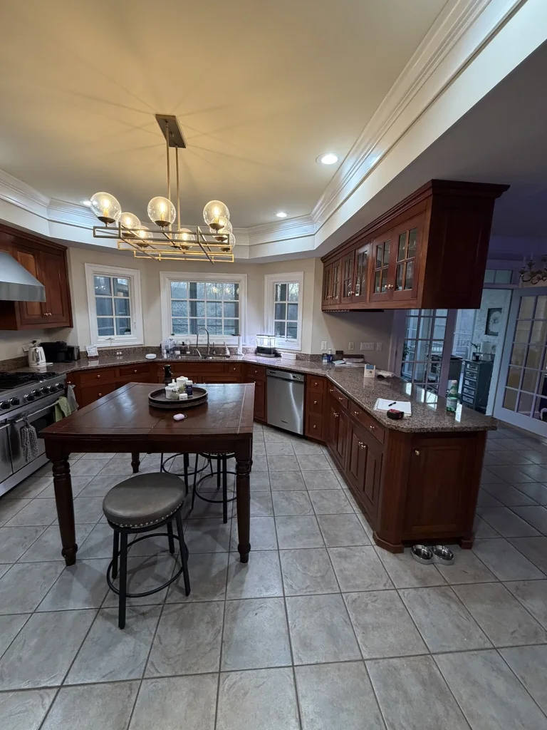 Original Ford’s Colony kitchen with wood cabinetry, overhead cabinets, and a small central table