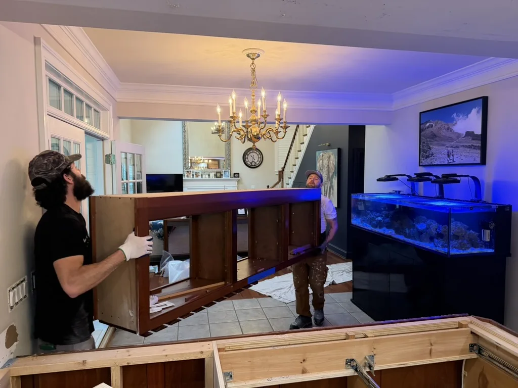 Crew removing the original overhead kitchen cabinets during demolition