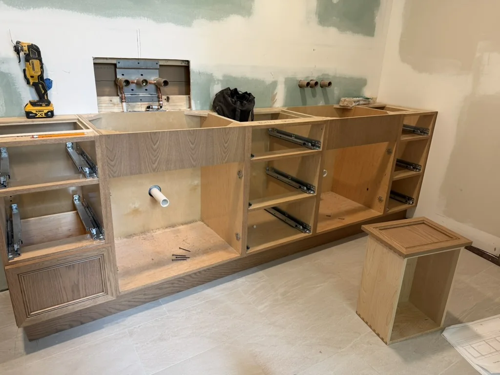 Stained white oak double vanity installed before the quartz countertop and wall finishes