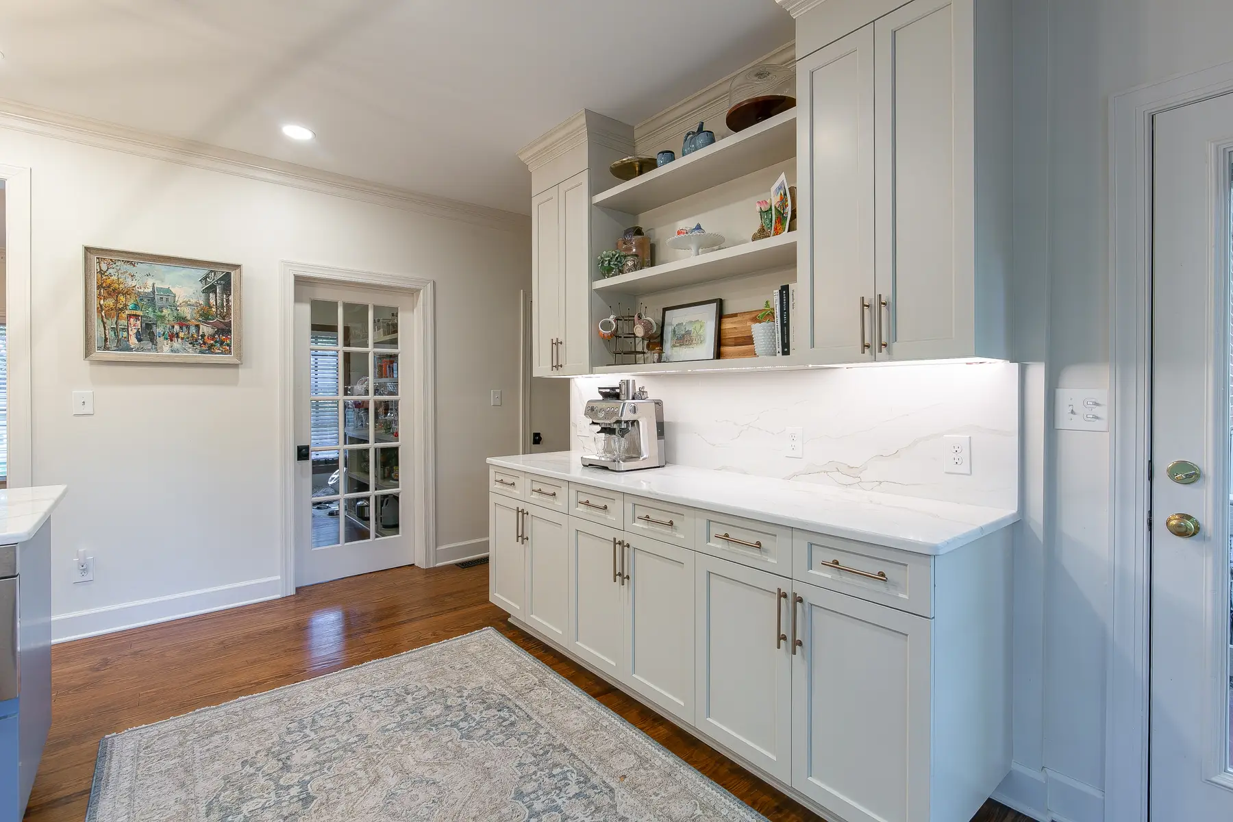 Dedicated Kingsmill kitchen coffee bar with shaker cabinetry, open display shelves, stone backsplash, and undercabinet lighting