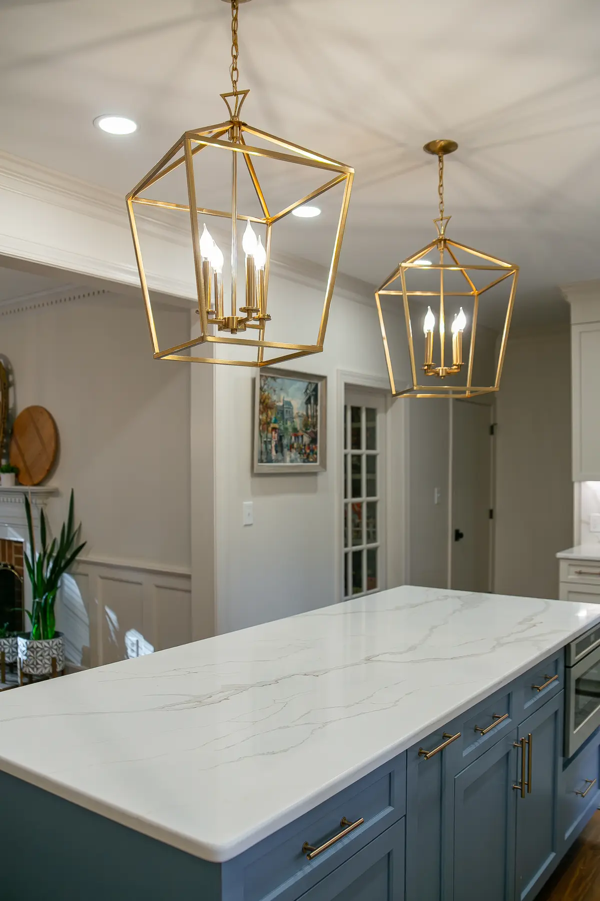 Blue island and bright stone countertop beneath oversized brass lantern pendants in a Kingsmill kitchen